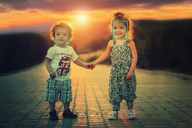 A photo of two children with green detection boxes drawn around both faces